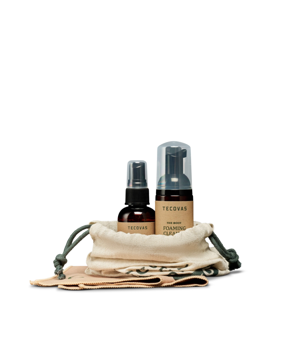 Two Tecovas shoe care products—a spray bottle and a foaming cleaner—are displayed upright in a small drawstring pouch with two cloths on a white background.