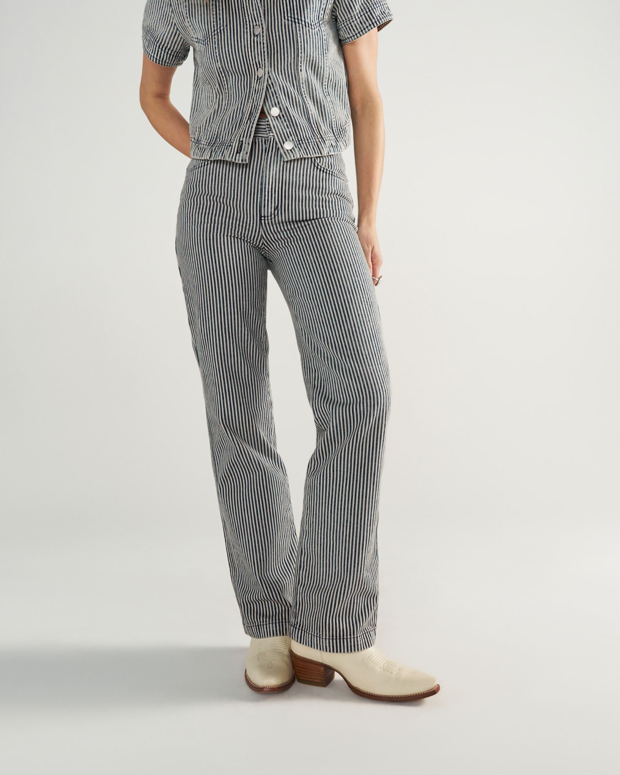 Person wearing a short-sleeve, button-up shirt and matching striped pants with white heeled shoes, standing against a plain background.