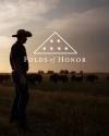 A person in a cowboy hat stands in a field with cattle at sunset. The "Folds of Honor" logo with stars and a triangle is displayed in the sky above.