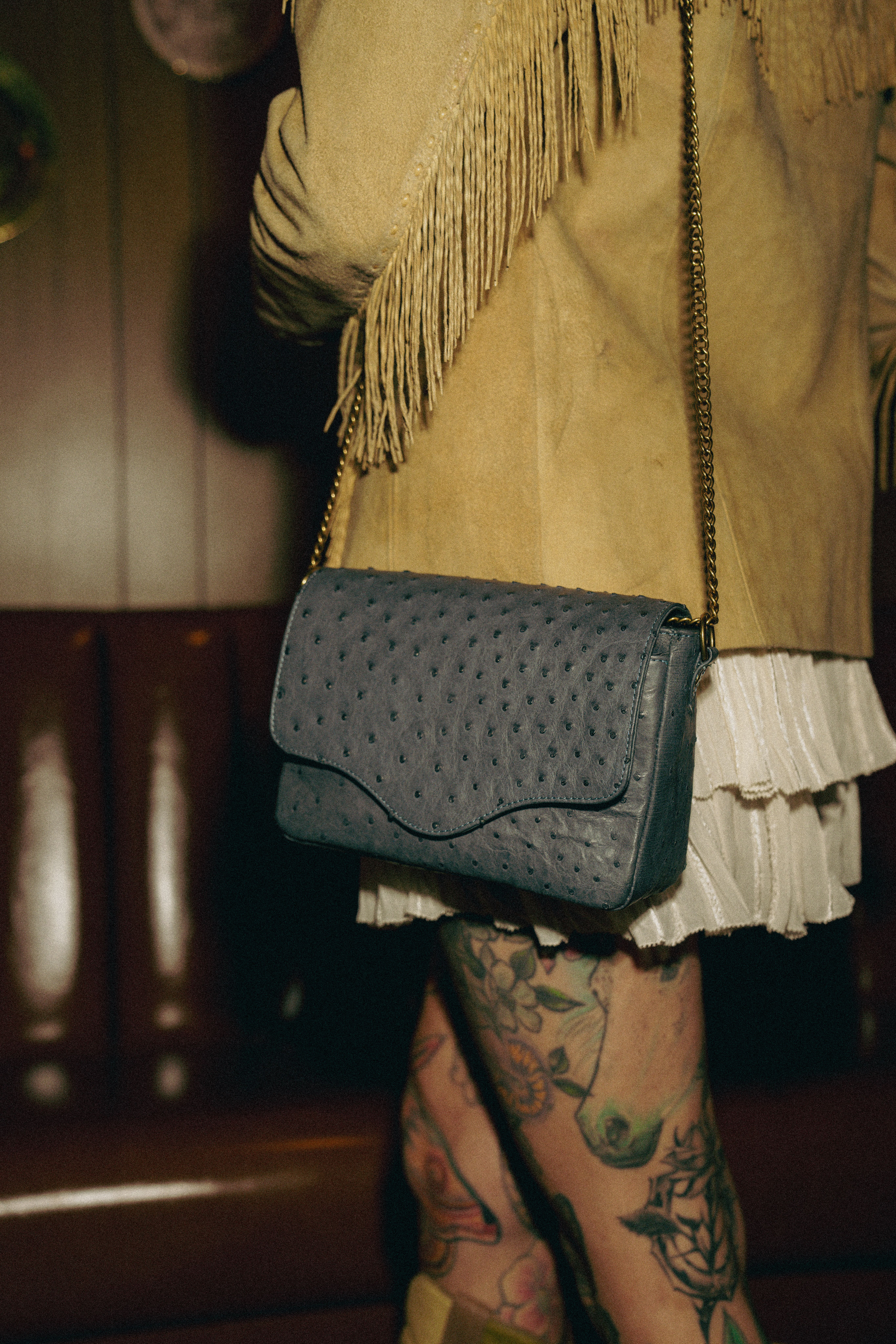A display of various leather handbags and wallets, including two large totes, two crossbody bags, and two wallets, arranged on a patterned bench.