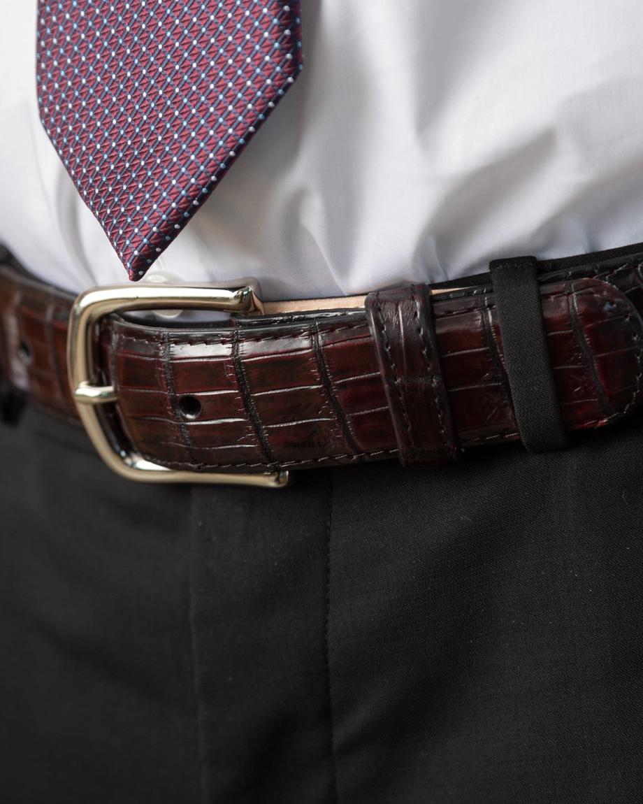 Black cherry crocodile belt close up on belt buckle around a man's waist