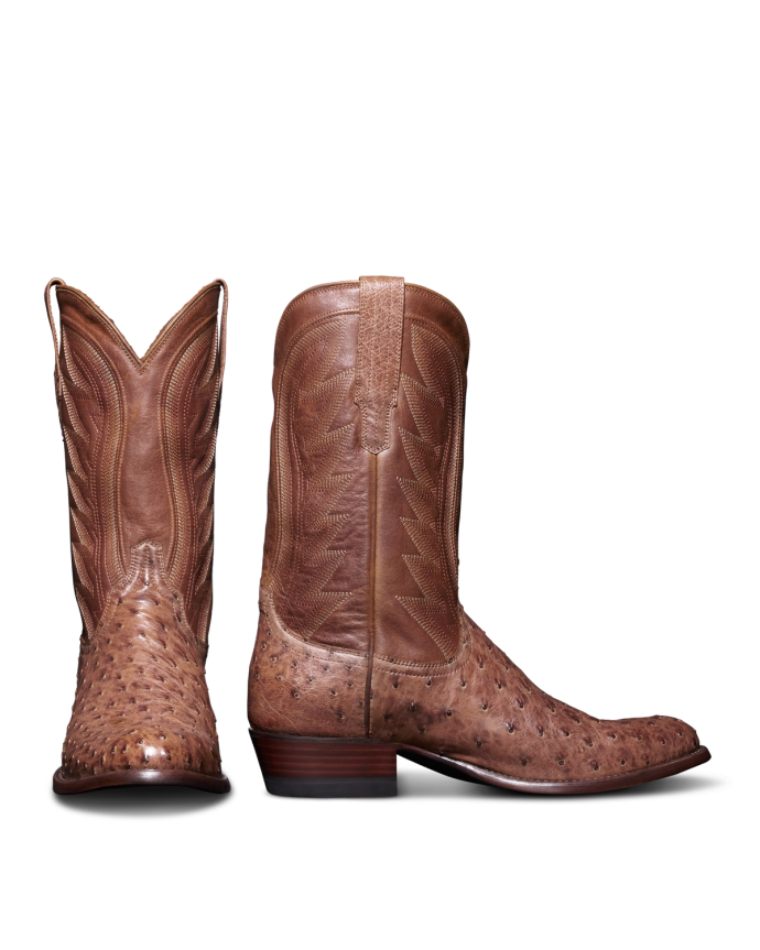 A pair of brown leather cowboy boots. The left boot is positioned upright, and the right boot is placed with the sole facing left.