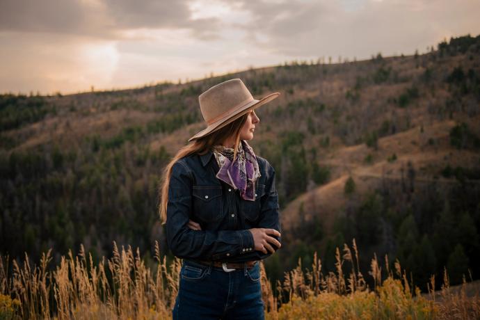 woman in a field by a mountain staring off