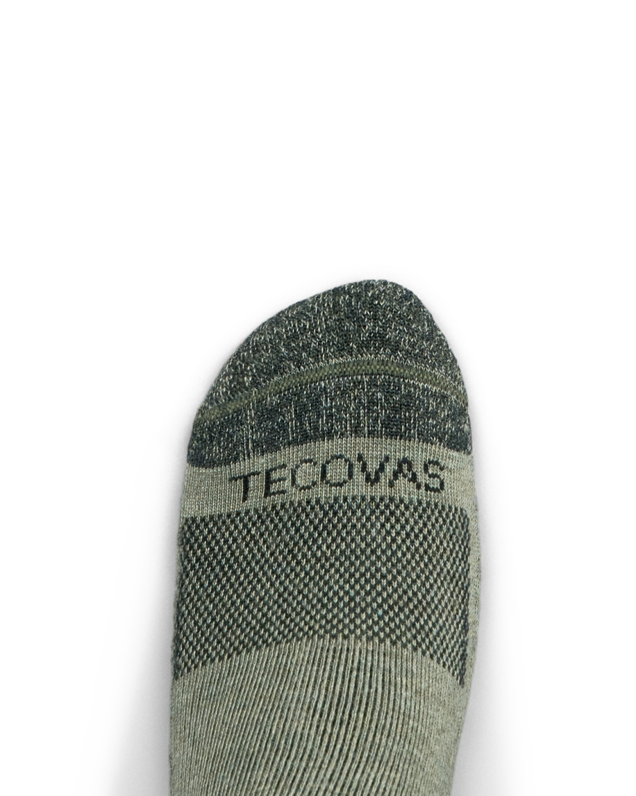 A close-up of a foot wearing a grey sock with the word "TECOVAS" printed across the top.