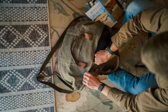 man zipping a weekender bag