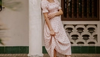 Woman leaning against column wearing a dress and white ostrich boots