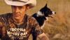 Man in cowboy hat wearing a Tecovas x Mossy Oak camo t shirt with a dog behind him staring into the abyss