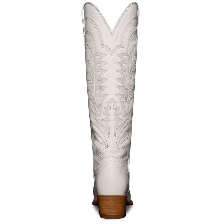 White cowboy boot with intricate stitching, viewed from the back, featuring a wooden heel and pointed top design.
