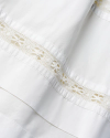 Close-up of a white fabric with lace trim featuring floral patterns.