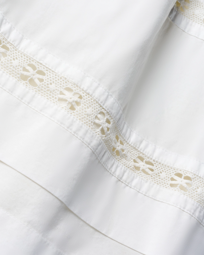 Close-up of a white fabric with lace trim featuring floral patterns.