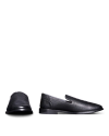 Black leather loafers against a black background, with one shoe standing upright and the other lying on its side.