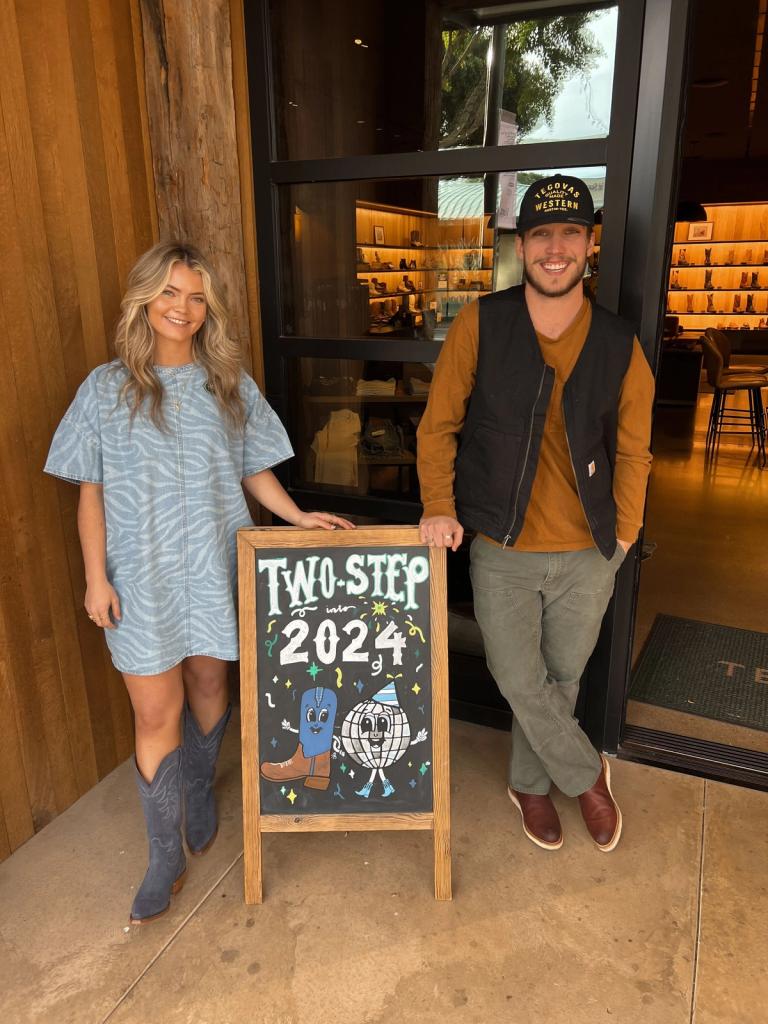 Two people standing in front of a sign that says two steps 2024.