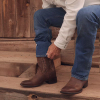 Man putting on The Doc cowboy boot under jeans