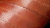Close-up of brown leather with visible stitching and a smooth, glossy finish.