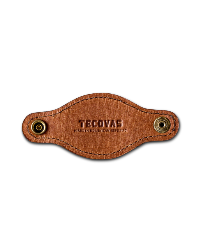 A brown leather piece with "Tecovas" and "Made in Dominican Republic" embossed, featuring two metal snaps on either end.