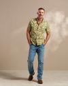 Man wearing a short sleeve camo shirt and jeans in a photo studio