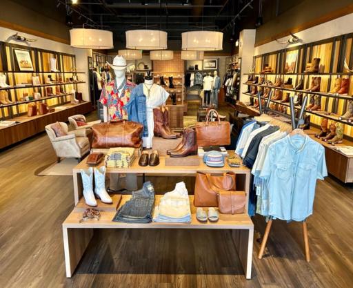 Interior of a boot store with shelves of various styles of cowboy boots, highlighting different patterns and colors, in a well-lit wooden display.