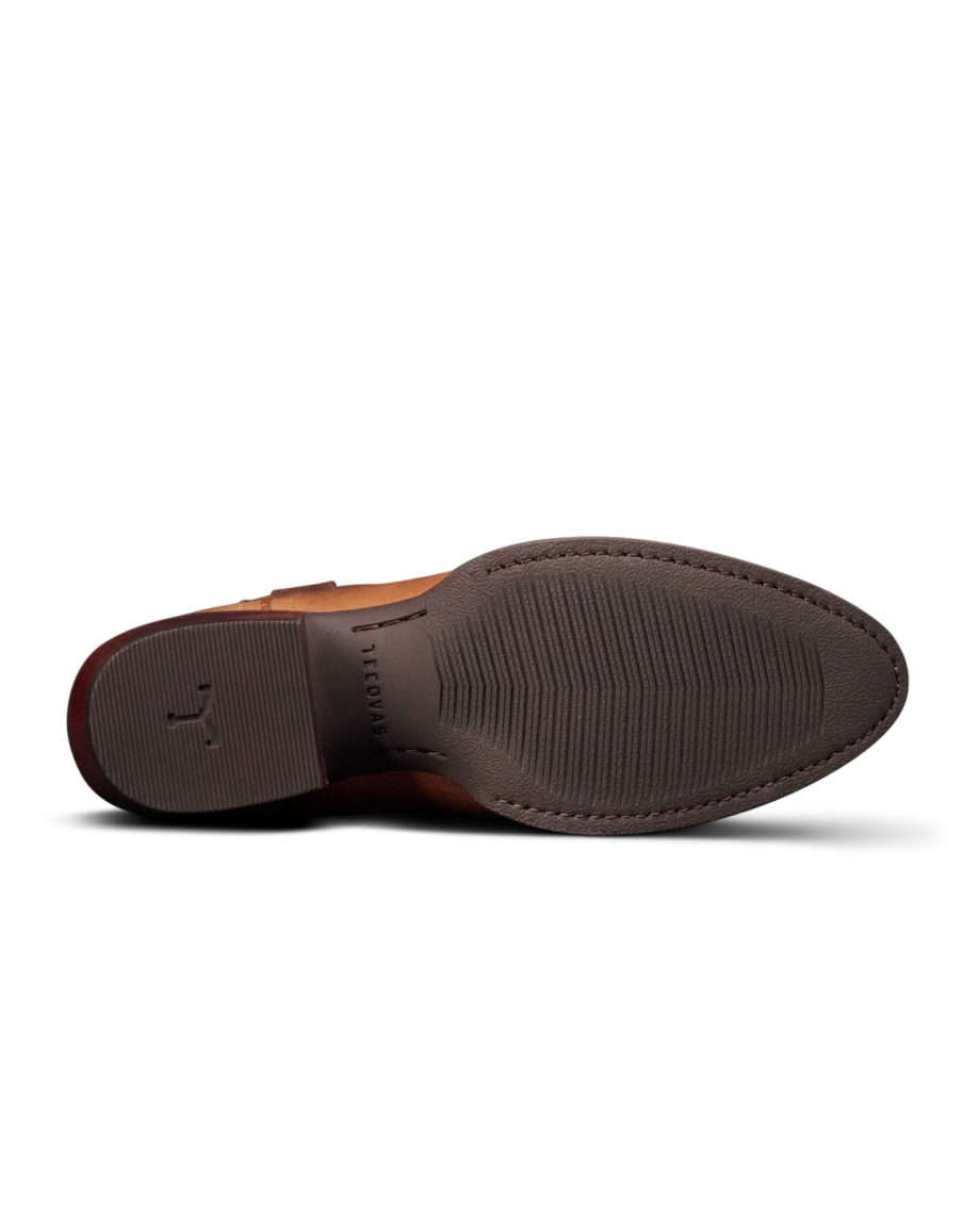 The Britt in Latte Goat. Brown leather dress shoe shown from the bottom, displaying a textured rubber sole with a small emblem and the word "FLORENTINI" embossed near the center—a refined style inspired by The Britt Goat collection.