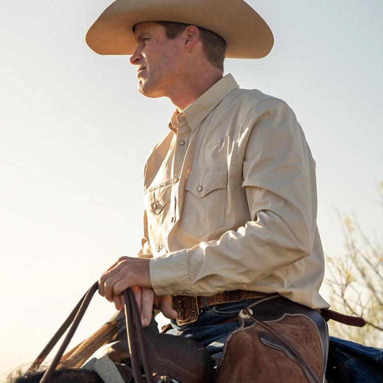 a man on a horse in a pearl snap button down and a cowboy hat