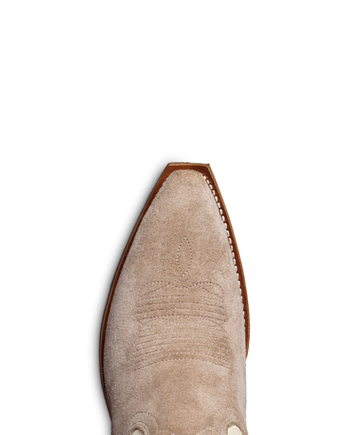 Close-up of the toe of a beige suede cowboy boot with stitch detailing, isolated on a black background.