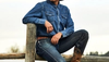 Cowboy in hat and boots sitting on a fence