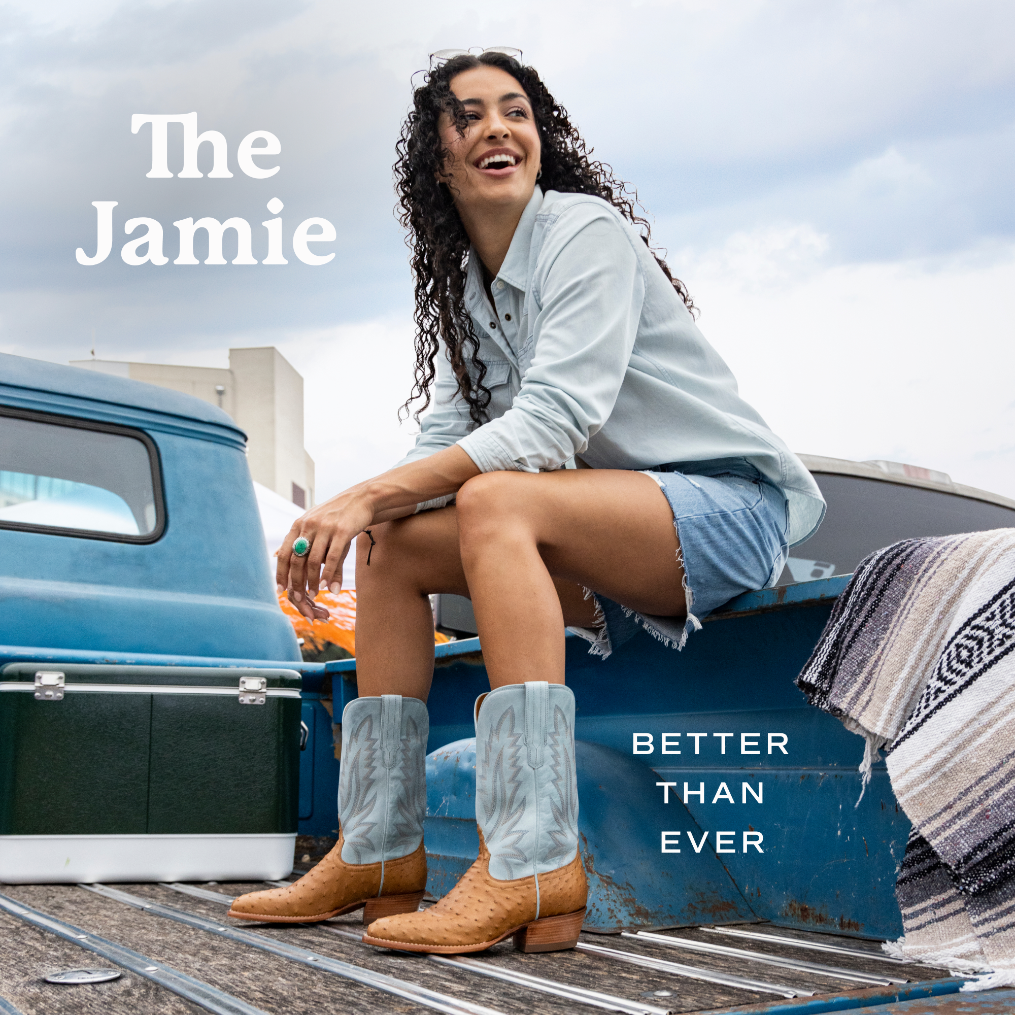 A woman with curly hair sits on the bed of a truck, wearing a light blue shirt, denim shorts, and cowboy boots. Text reads "The Jamie" and "Better Than Ever.