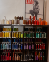 Shelves filled with colorful spools of thread organized by hue, with a "LIFE" magazine poster featuring a person in cowboy attire above.