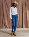 Full body view of woman wearing a white pearl snap and jeans in a studio
