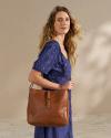 Closeup of woman wearing a blue dress and brown handbag in a photo studio