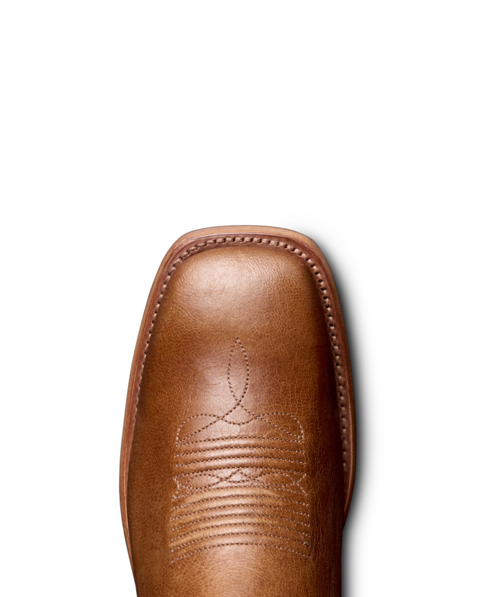 Close-up of a brown cowboy boot with detailed stitching on the toe, against a plain black background.