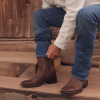 Man adjusting jeans over his brown cowboy boots