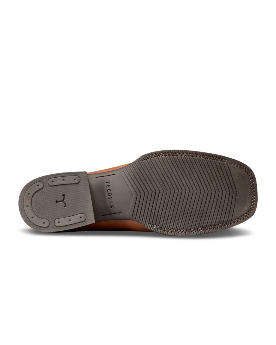 The Dusty in Mesa Goat. The image shows the bottom view of a brown dress shoe from The Dusty Goat, with a gray rubber sole featuring textured grip and the word “TECTONIC” engraved near the arch.