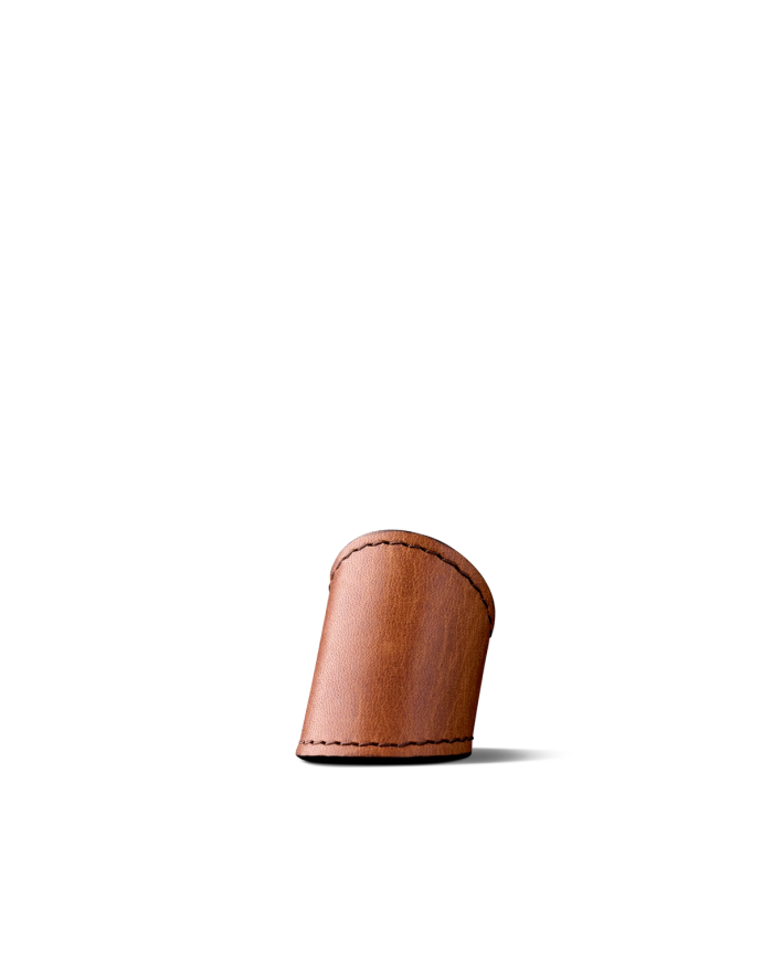 A small, brown leather keychain holder with stitching along the edges is pictured on a plain, black background.