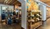 A store interior with shelves displaying hats and clothing. A large mural depicting a desert scene is on the wall. The ceiling features wooden beams.