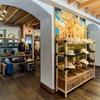 A store interior with shelves displaying hats and clothing. A large mural depicting a desert scene is on the wall. The ceiling features wooden beams.