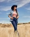 Woman wearing a cowgirl hat standing in a field