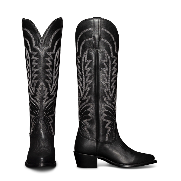 Black cowboy boots with intricate white stitching, featuring a pointed toe and a chunky heel, displayed upright and in profile.
