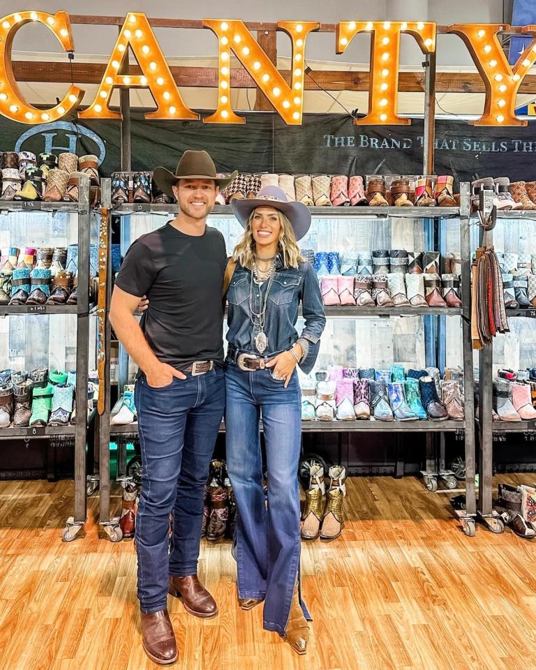 Couple standing inside at a boot event wearing fun western denim outfits
