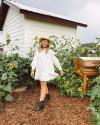 Woman in white sundress and boots in front of sunflowers