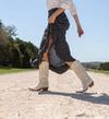 Person walking on a gravel road wearing cowboy boots and a polka dot dress.