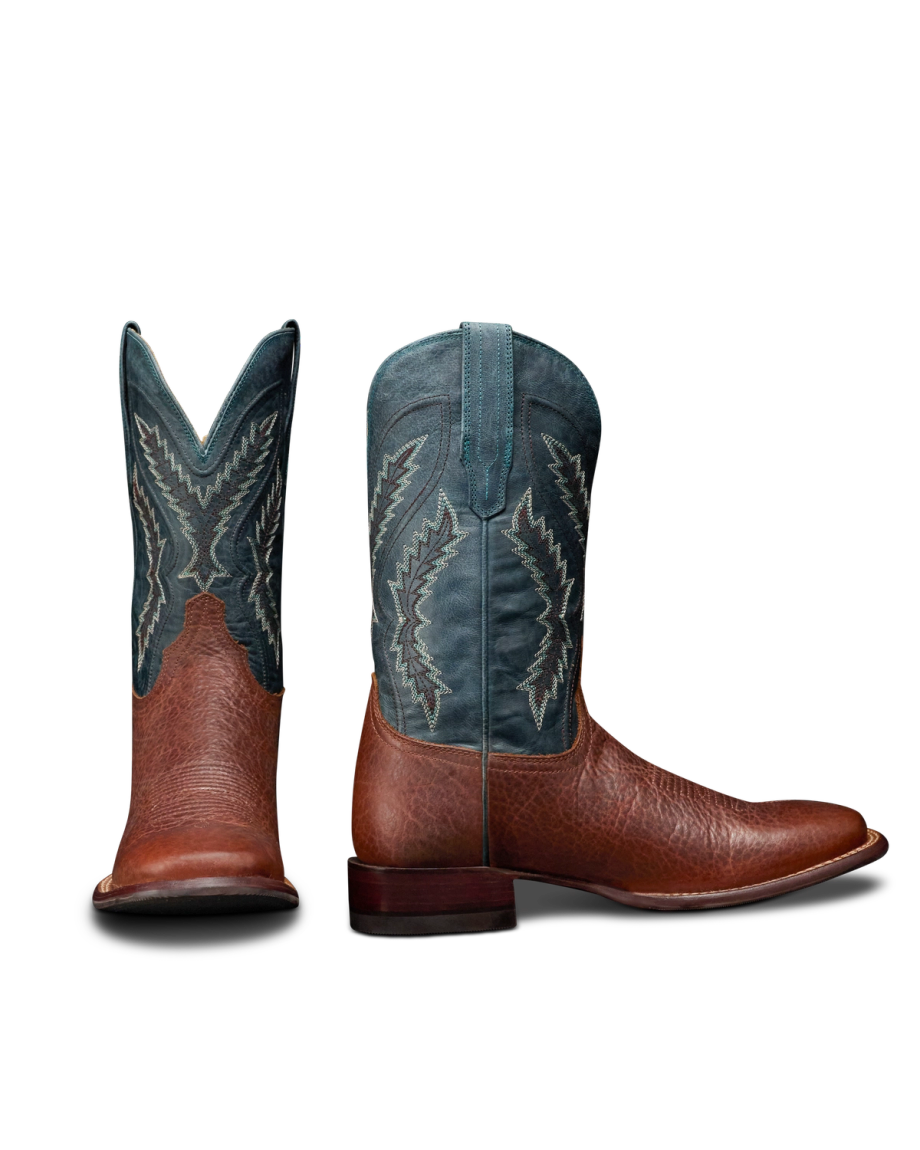 The Doc in Burnt Umber / Blue Cowhide. A pair of cowboy boots with burnt umber cowhide foot and heel, and a blue shaft featuring white decorative stitching. One boot is shown from the front, the other from the side.