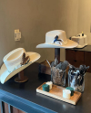 A collection of stylish hats displayed on a shelf with decorative items, including a wooden box and glass vases with plants.