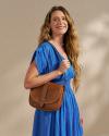 Closeup of woman wearing a blue dress and brown handbag in a photo studio