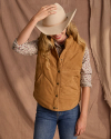 Woman wearing a cowboy hat, suede puffer, floral button down and jeans.