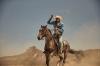 A cowboy in a denim jacket and straw hat swings a lasso while riding a galloping horse across the desert.