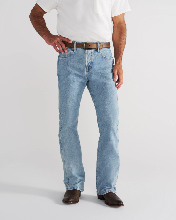 A man wearing a white t-shirt, brown belt, light-wash blue jeans, and brown leather boots.