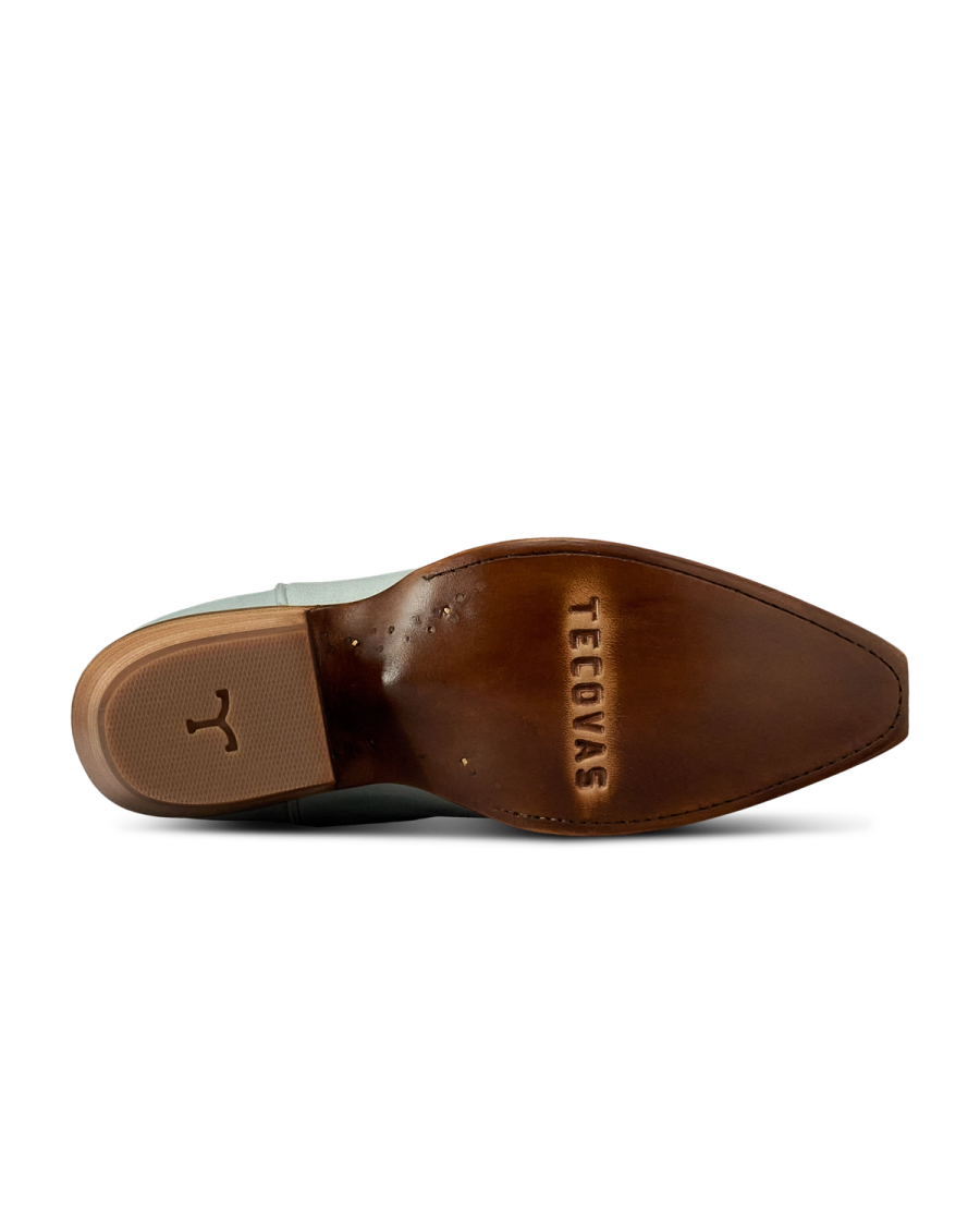 The Annie in Slate Blue Cowhide. Bottom view of The Annie Cowhide boot sole in brown leather, featuring the Tecovas brand name and a small bull logo near the heel.