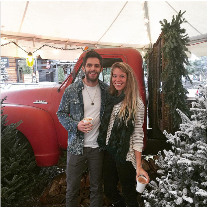 Couple standing by a red truck and Christmas tree