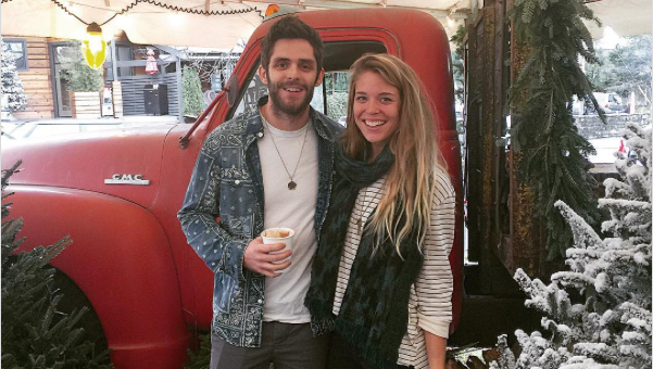 Couple standing by a red truck and Christmas tree