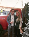 Couple standing by a red truck and Christmas tree